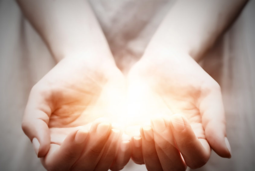The light in young woman hands. Sharing, giving, offering, protection