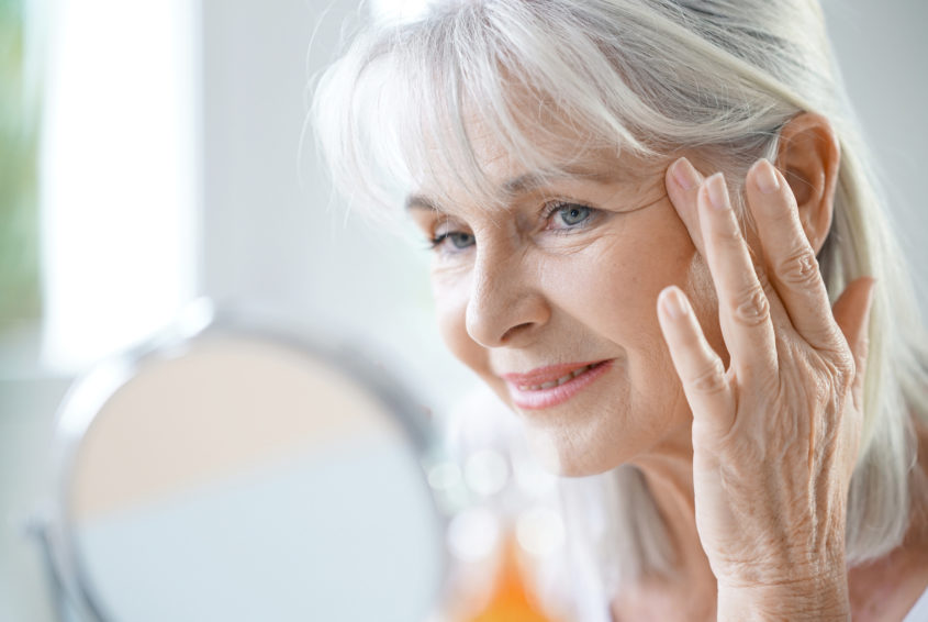 Portrait of senior woman applying anti-aging cream