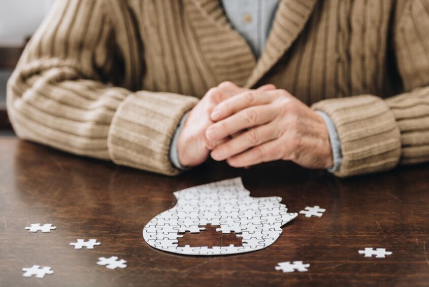 cropped view of senior man playing with puzzles on table Demencja starcza-Alzheimer