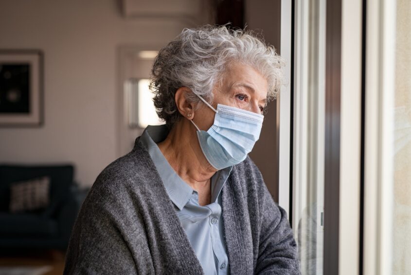 Sad senior woman wearing face mask staying at home Senior w pandemii